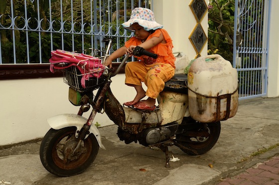 Una niña jugando con una antigua motocicleta