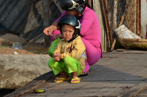 Un niño vietnamita descansando con el casco puesto al borde del Mekong
