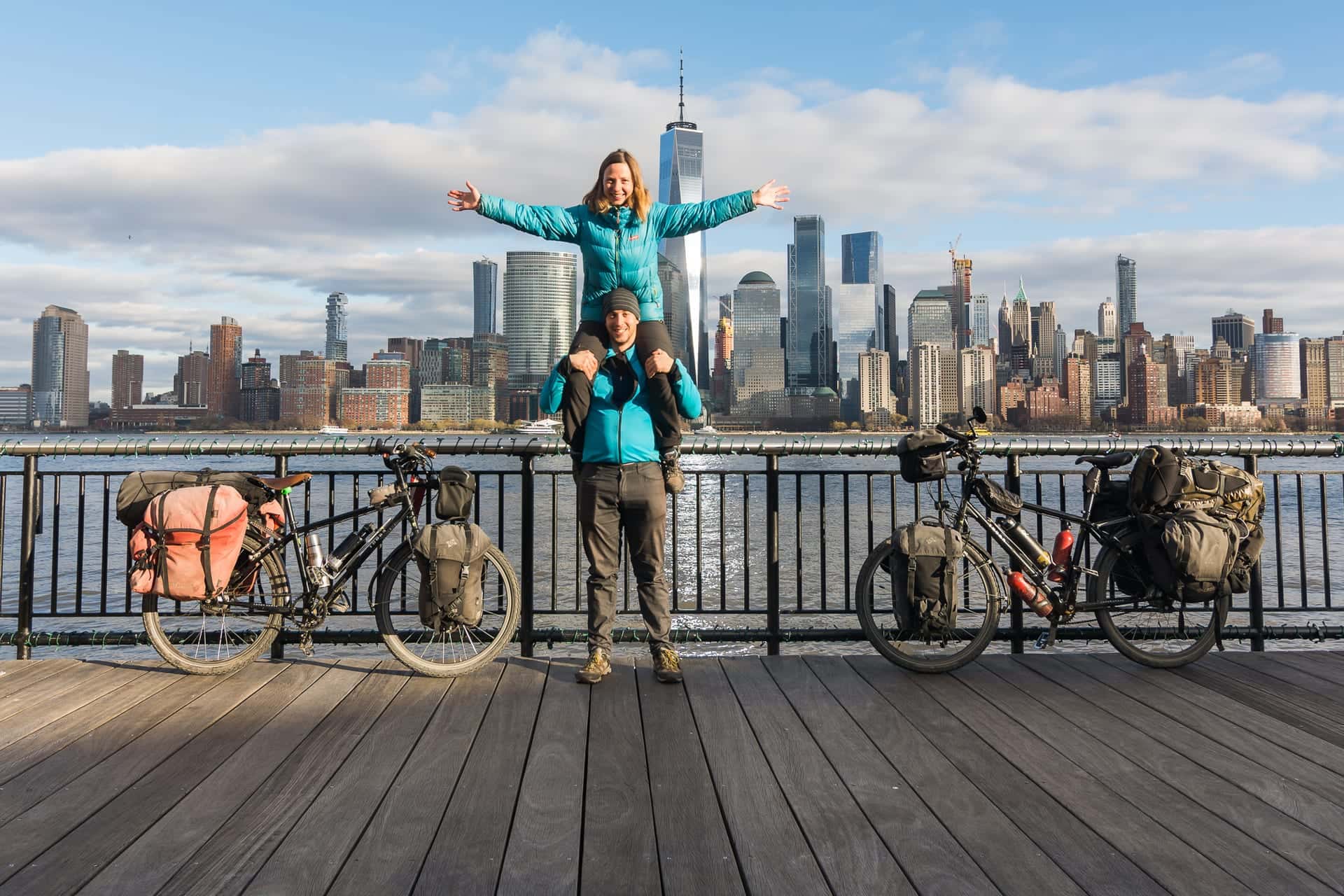 Pablo e Ilze con las bicicletas cargadas frente al skyline de Nueva York, al final de la vuelta al mundo