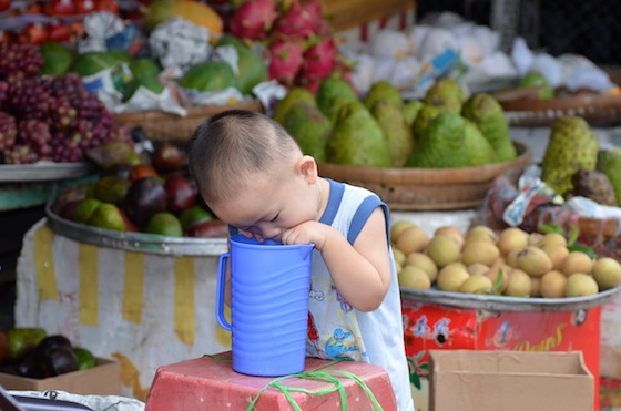 Un niño jugando en un puesto de frutas